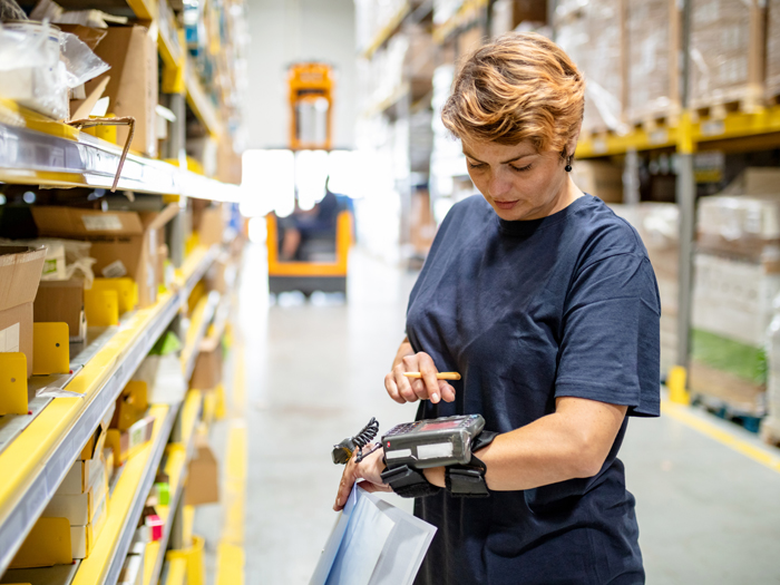 A warehouse worker checks a wearable tech device