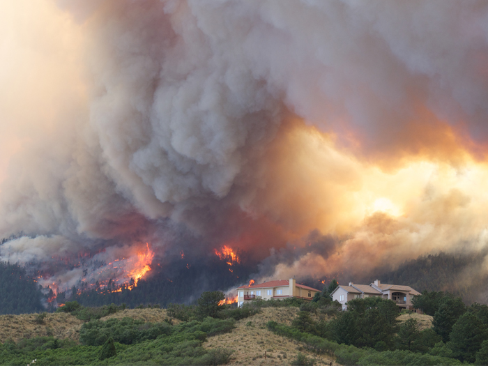 A wildfire rages across treed mountains in Colorado, threatening nearby homes.