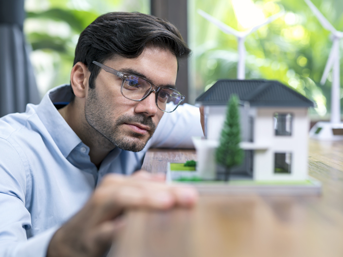 A man examines a small model of a single-family house.
