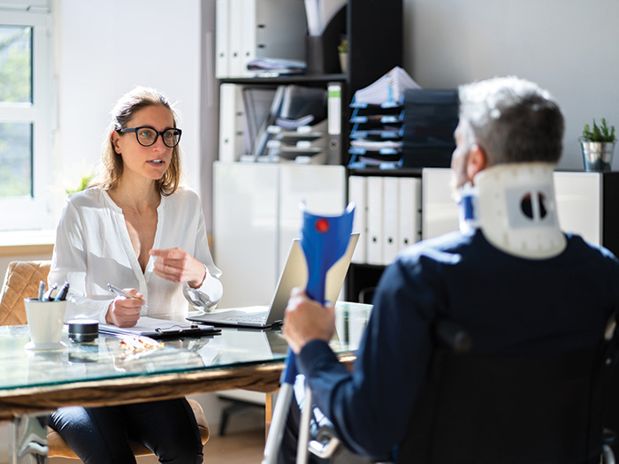 An injured worker speaks with a claims adjuster in an office environment