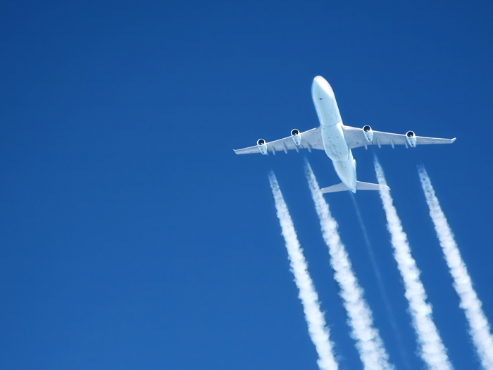 An airliner, seen from below, flies across the sky