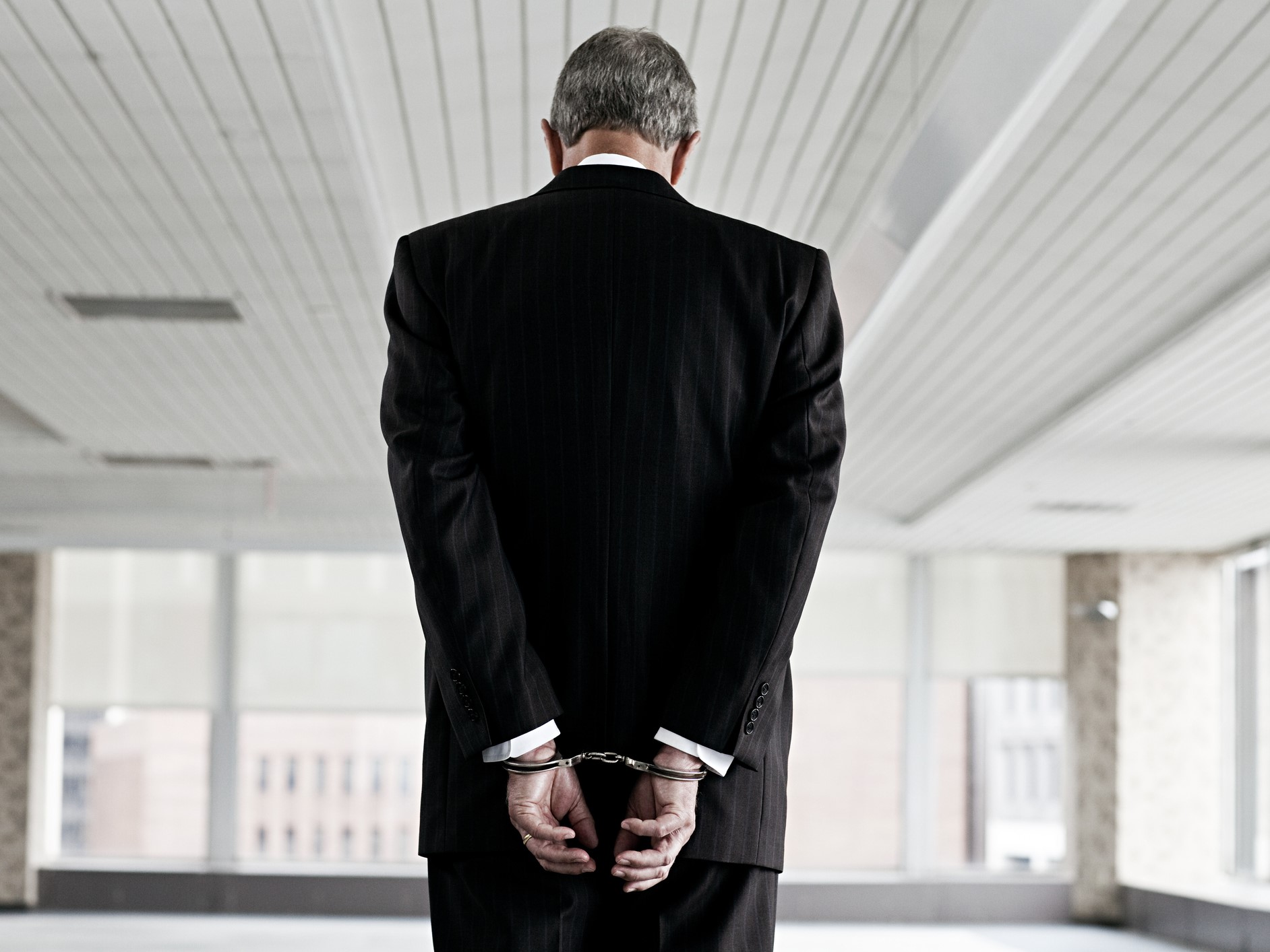 man in business suit with hands cuffed behind back