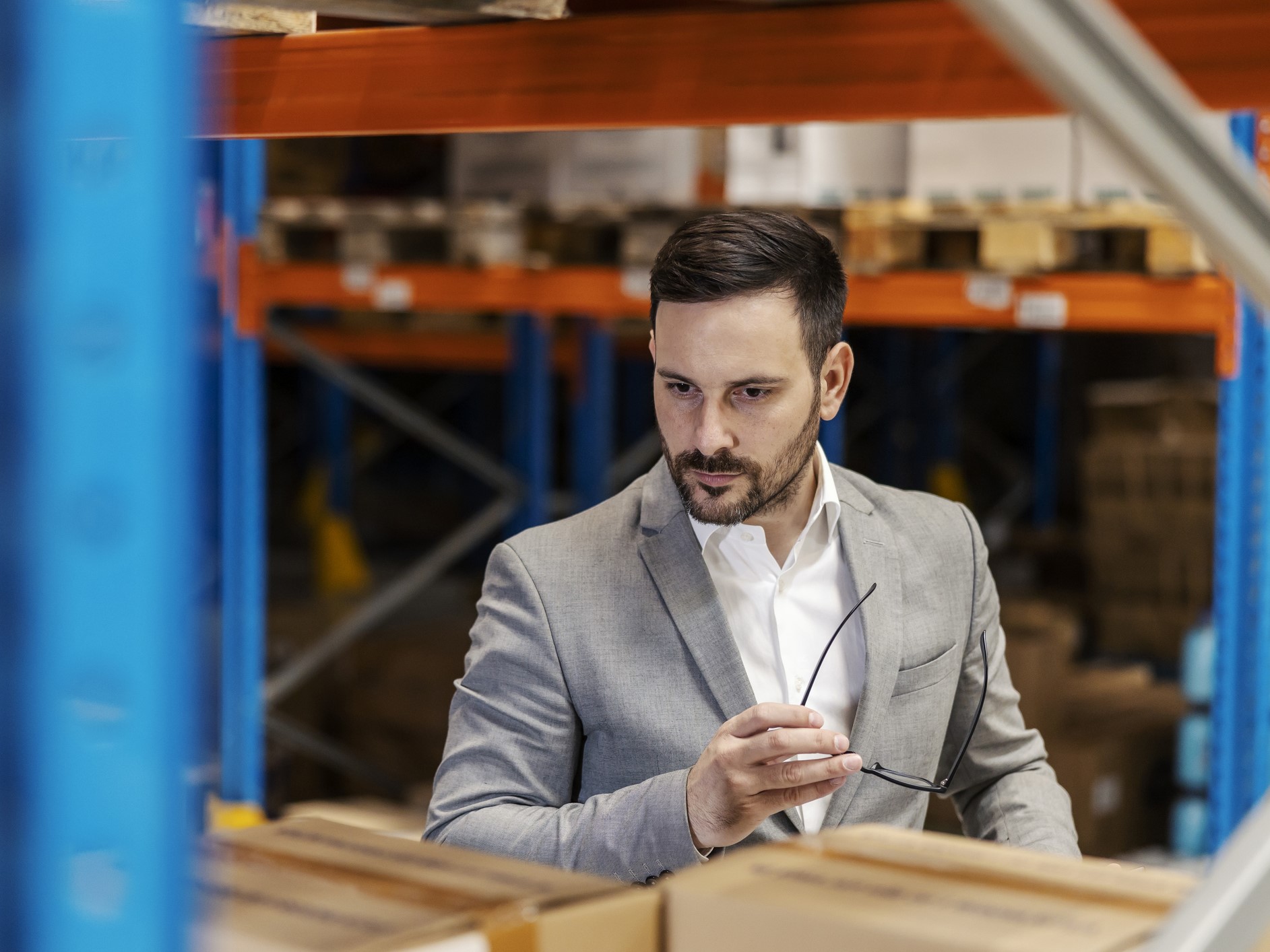 A serious manager is checking on goods in warehouse.