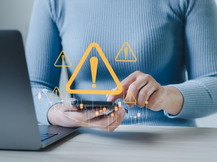 using smartphone and notebook at work desk with warning sign for caution