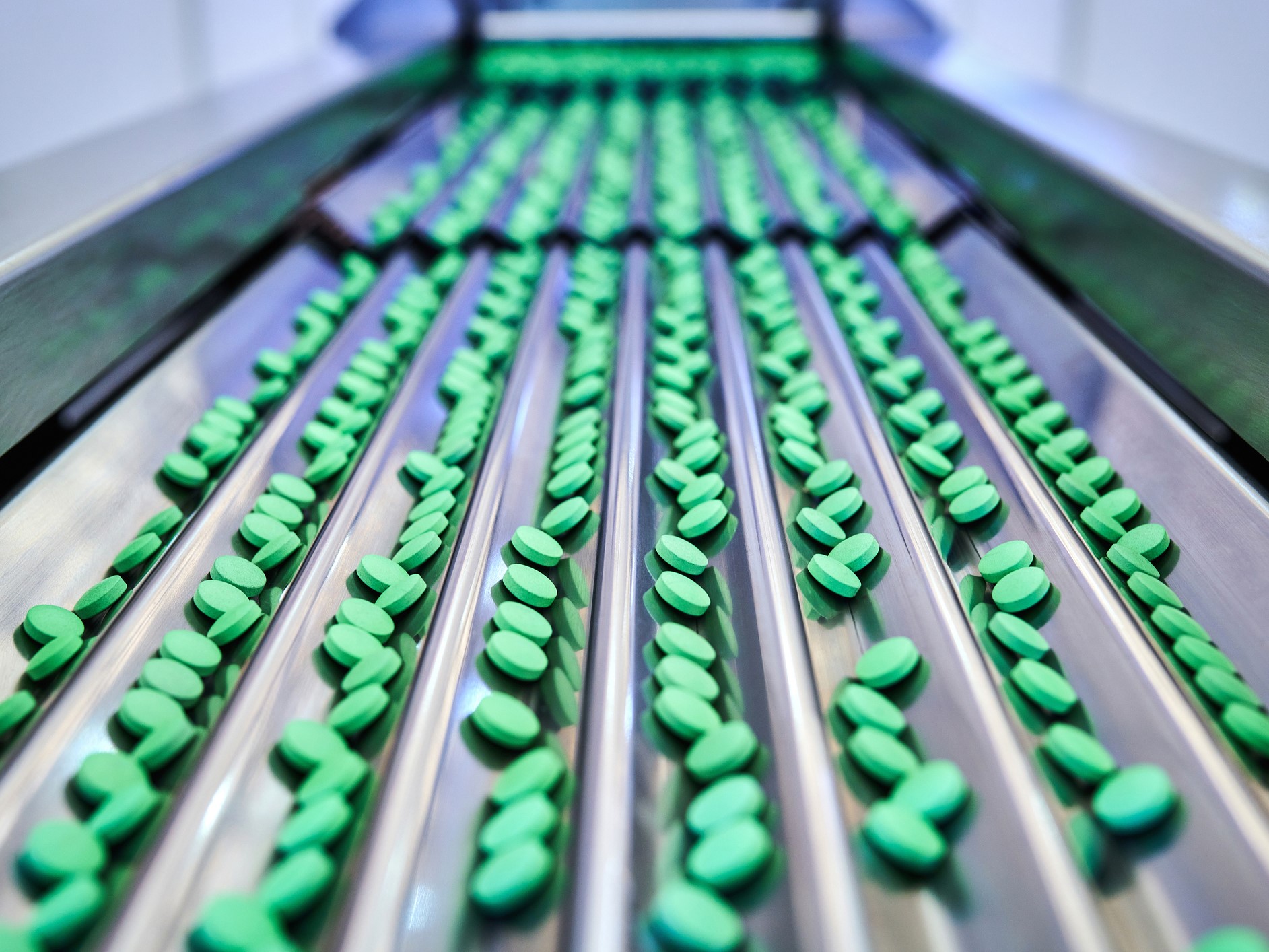 green pill at conveyor belt in the pharmaceutical factory
