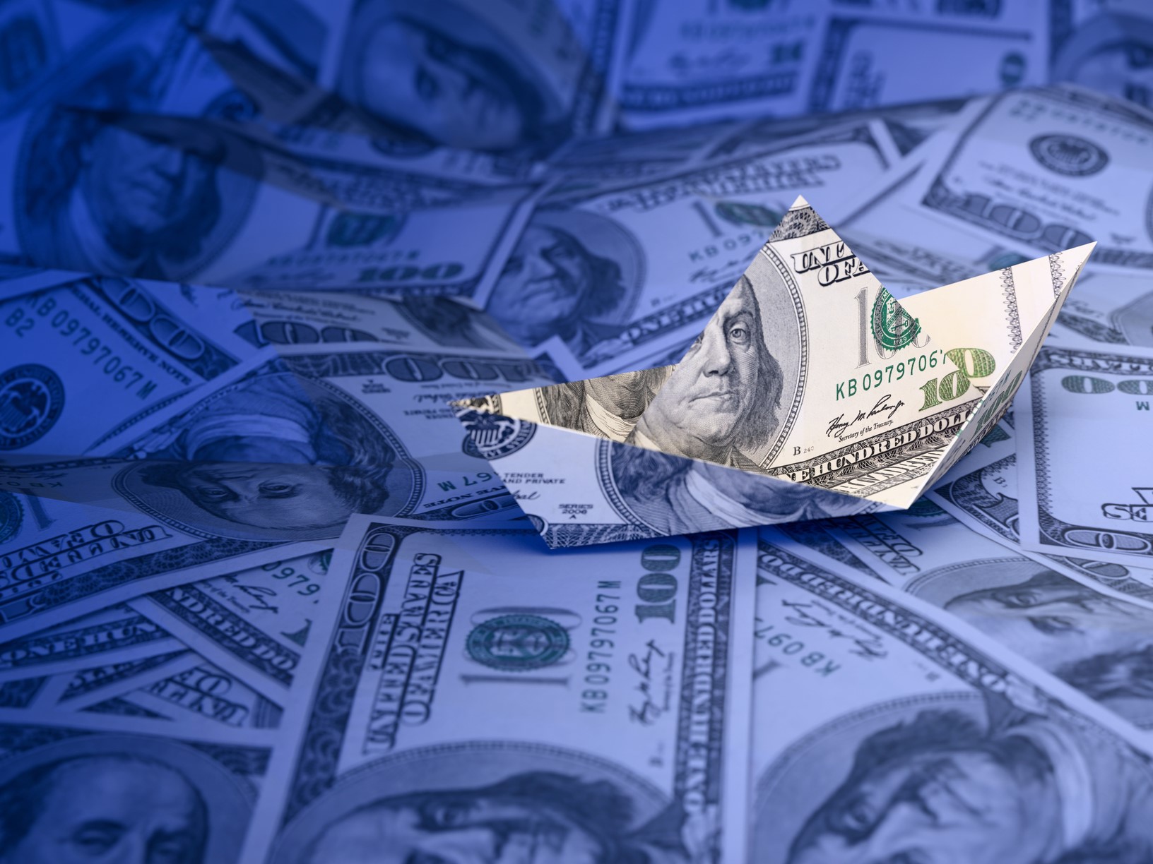 Paper boat made of money on dollar background