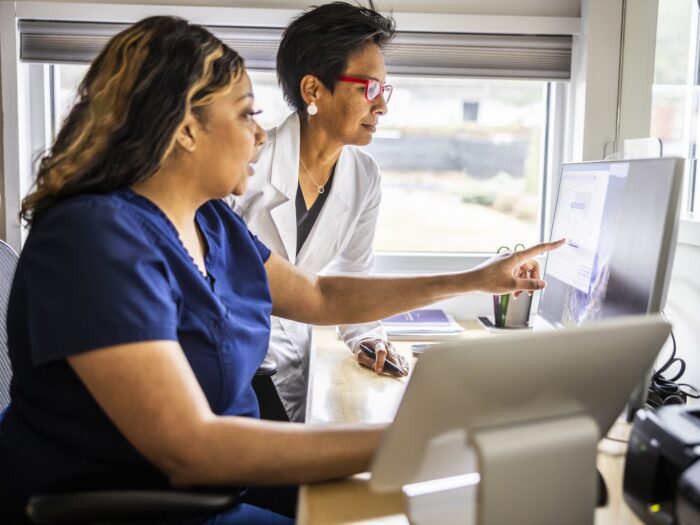Female doctor and nurse conferring at reception desk