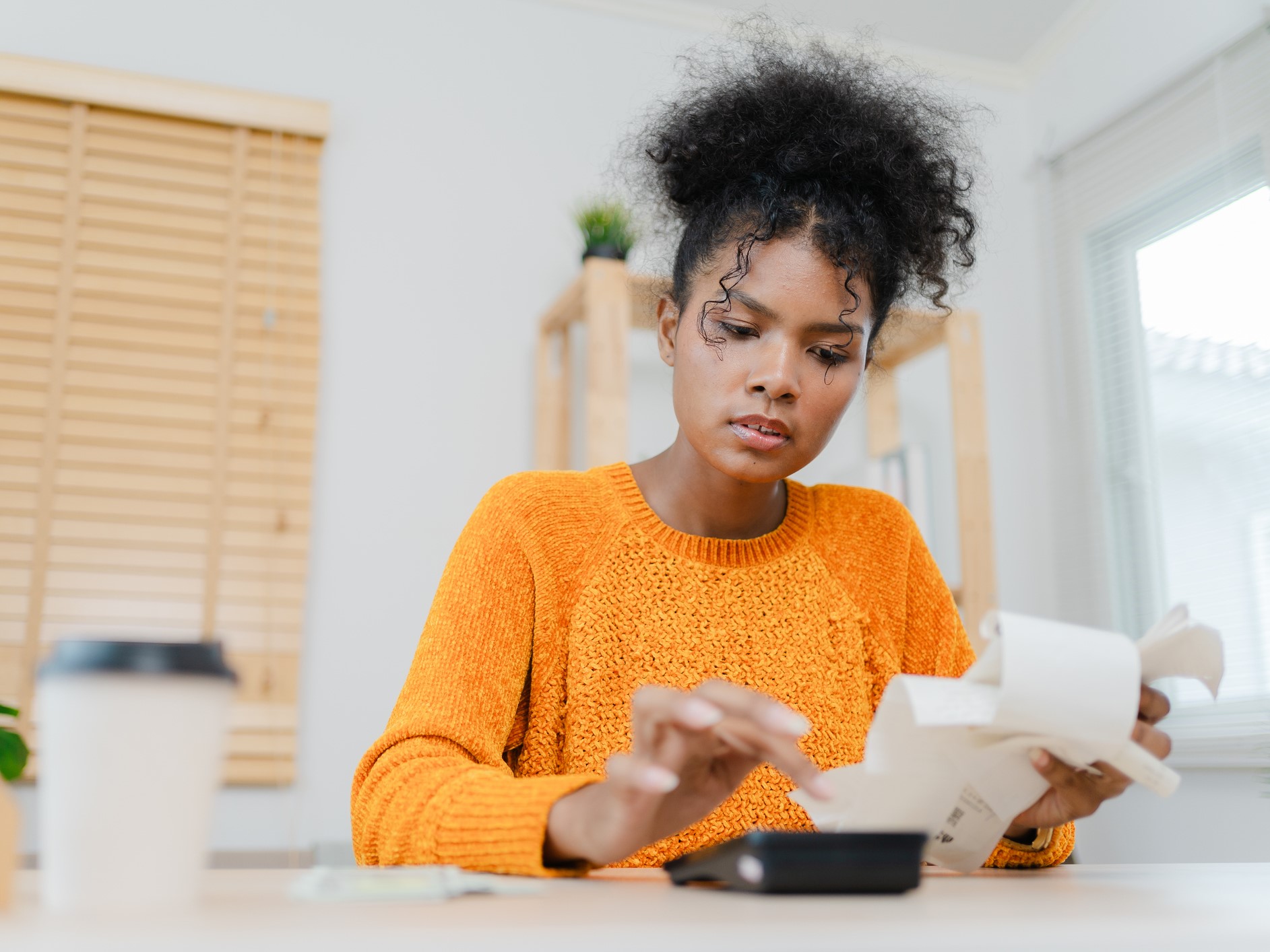 Woman is sitting at a table, focused on a calculator