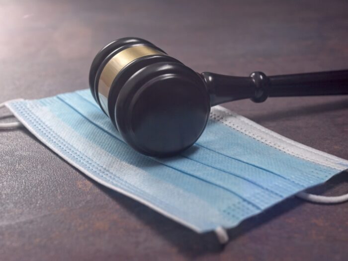 Close-up of a Judge Gavel Resting On A Protective Mask.